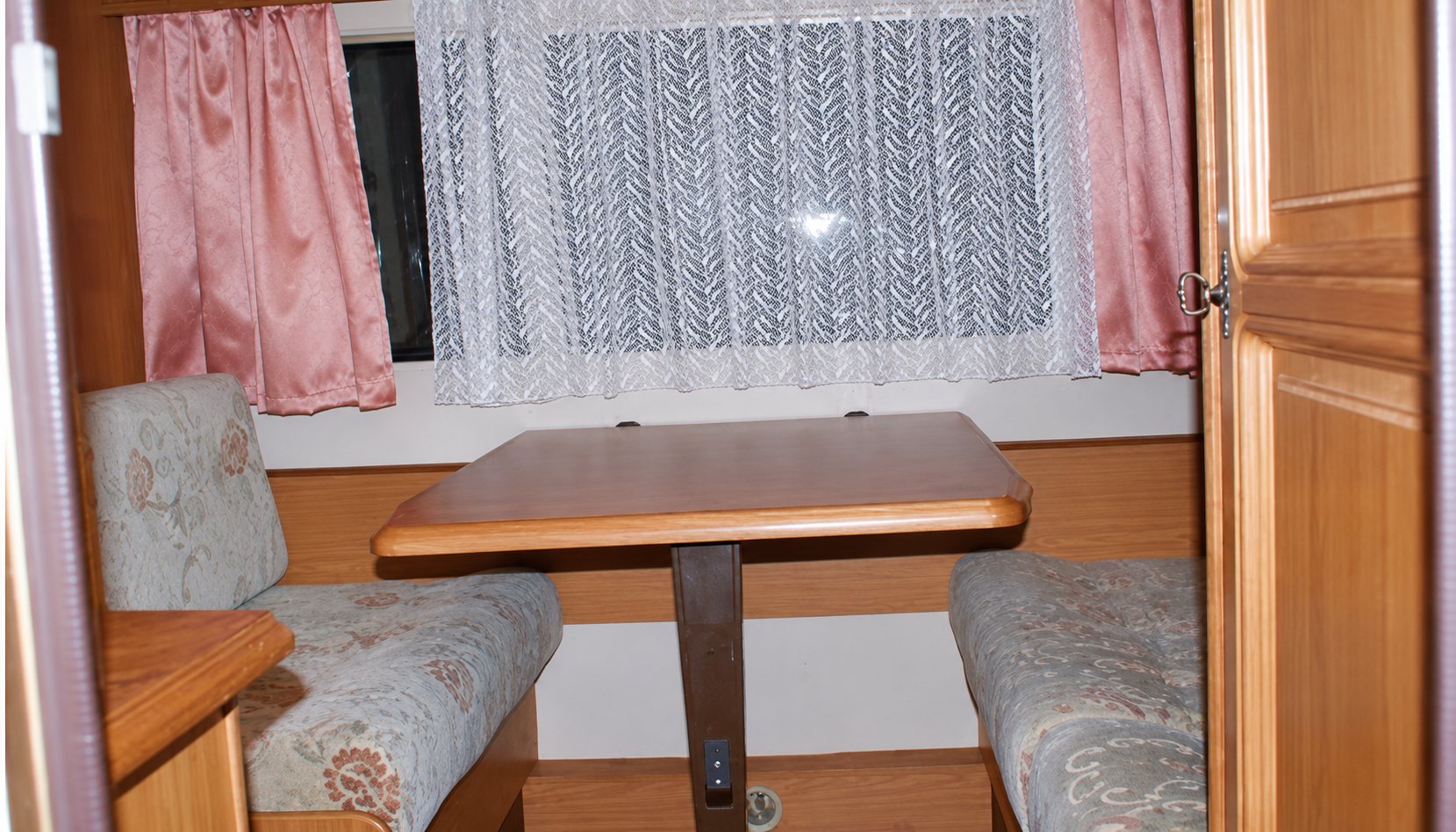 Coin repas de la caravane 1, table et banquettes fleuries