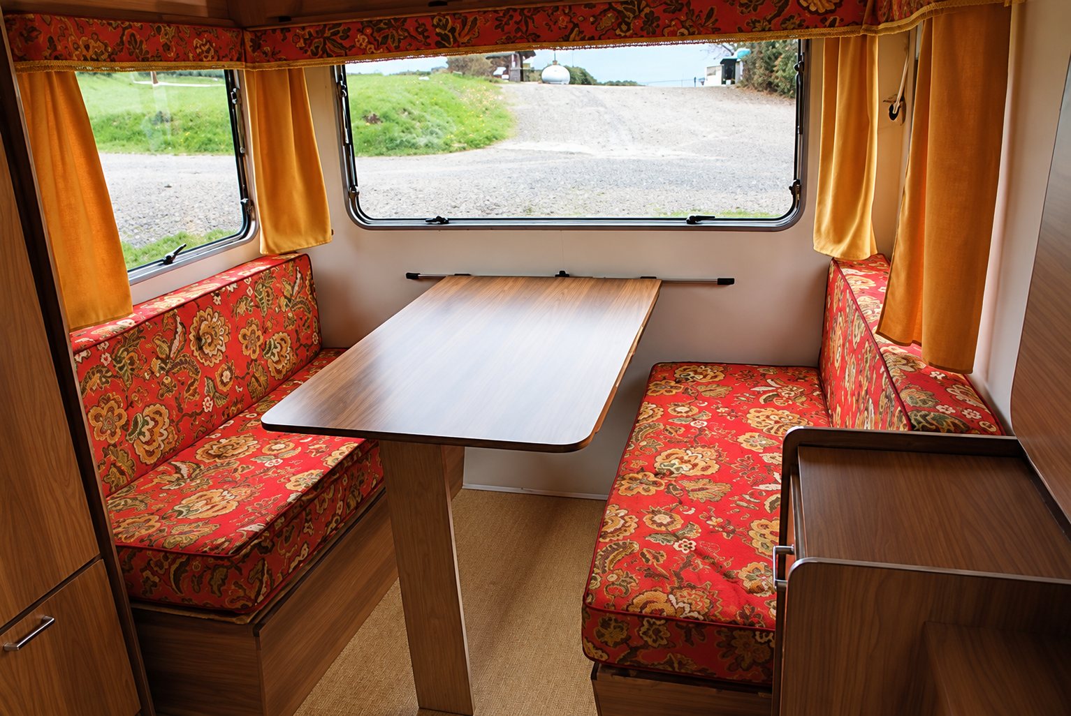 Intérieur de la caravane 2, banquettes rouges autour de la table